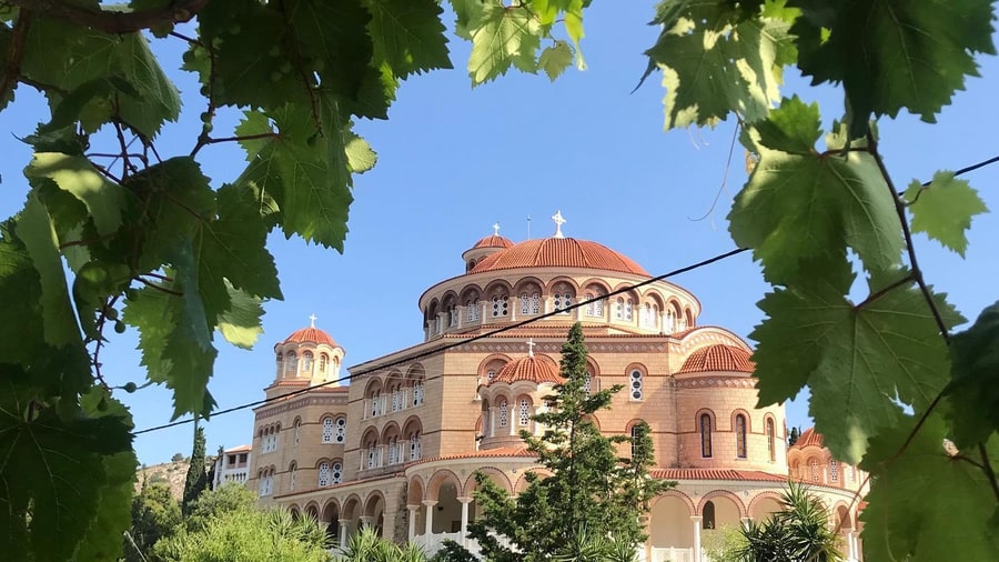 The domed church of Agios Nektarios framed by vine leaves on an Aegina day trip
