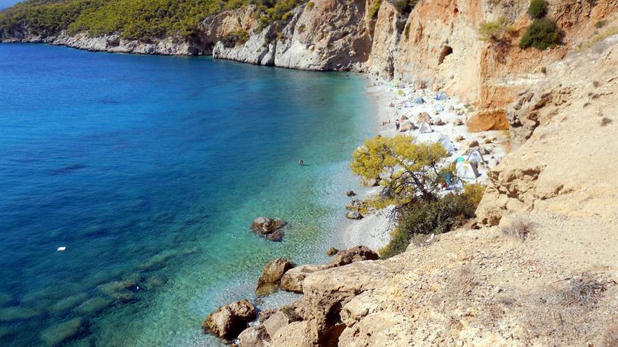 Rocky cove with clear blue water and pine trees on Agistri