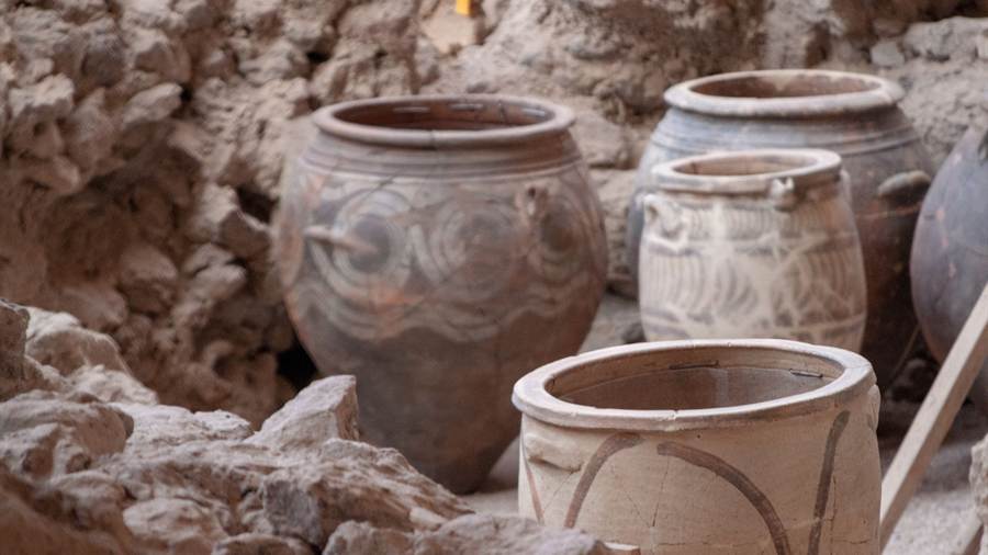 Large clay storage jars standing in the excavated ruins of Akrotiri, a sight on Akrotiri tickets