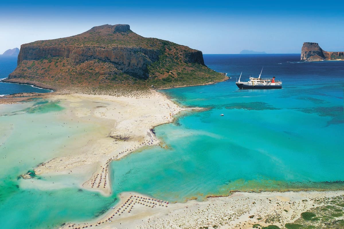 Aerial view of Balos lagoon and the island of Gramvousa with a boat in the bay, seen on a Balos lagoon cruise