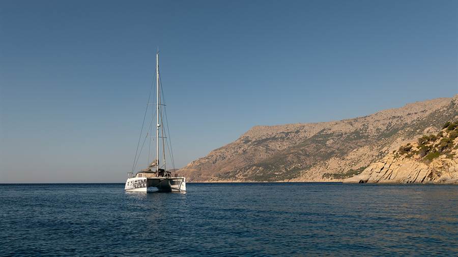 A sailing yacht at anchor off a dry headland in the Aegean