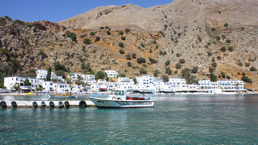 A boat moored off the white houses of Loutro on the south coast of Crete, a stop on a Crete boat trip