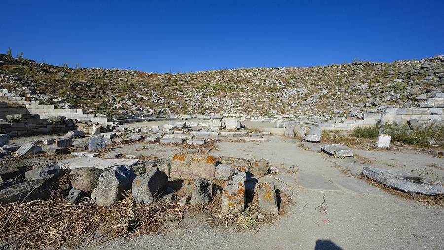 Ruins of the ancient theatre on the island of Delos under a blue sky