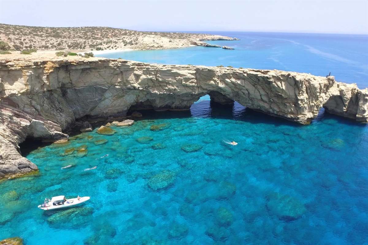 A rock arch over clear turquoise water on the coast of Gavdos, a stop on a Gavdos boat trip