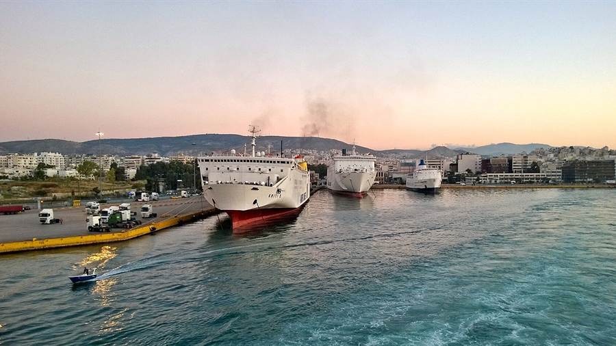 Ferries sailing in Piraeus harbour at dusk with the coast behind