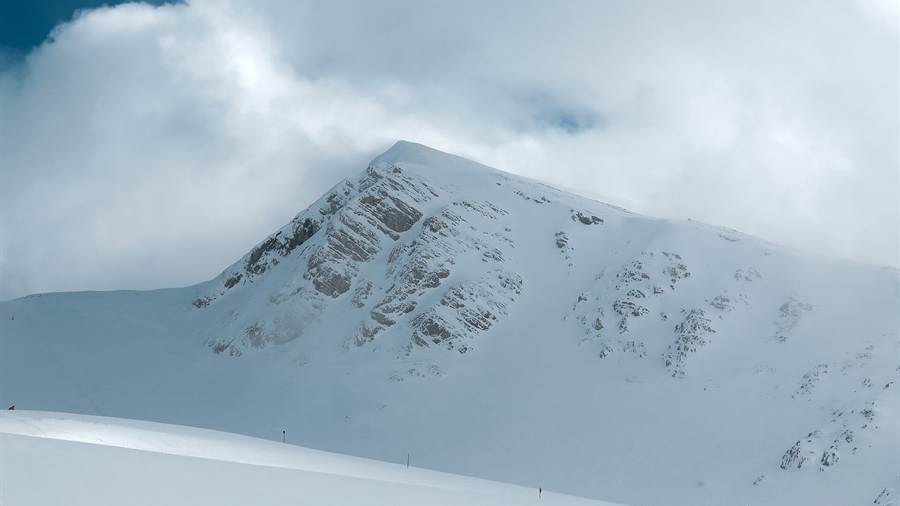 Snow-covered slopes and summit of Mount Parnassus beneath drifting cloud
