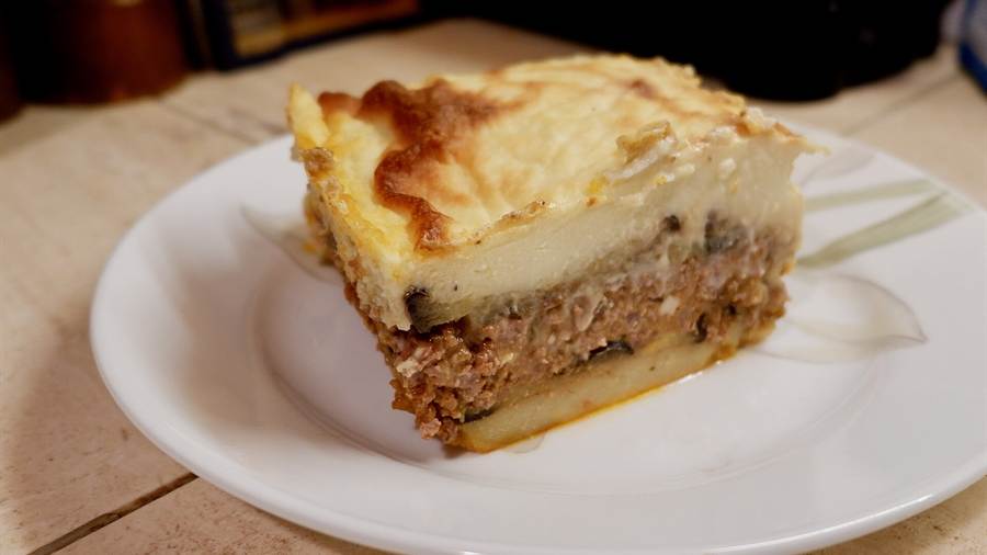 A slice of moussaka with a golden top, one Greek food to try