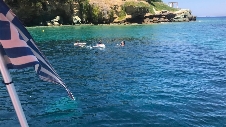 Snorkellers swim in clear water off the rocky coast near Agia Pelagia on a Heraklion boat trip