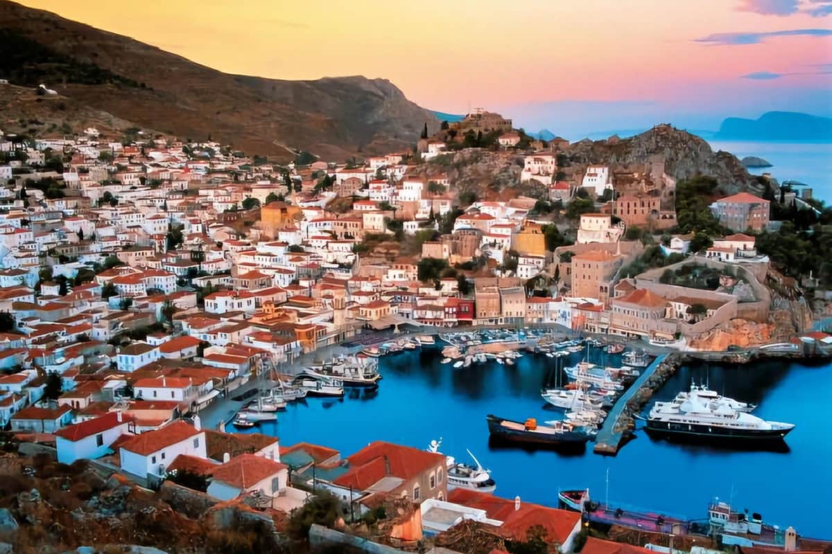 Hydra harbour and the town rising up the hills at dusk on a Hydra day trip