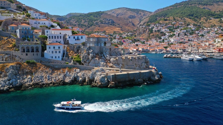 A boat leaves the harbour entrance of Hydra on a Hydra Poros Aegina cruise