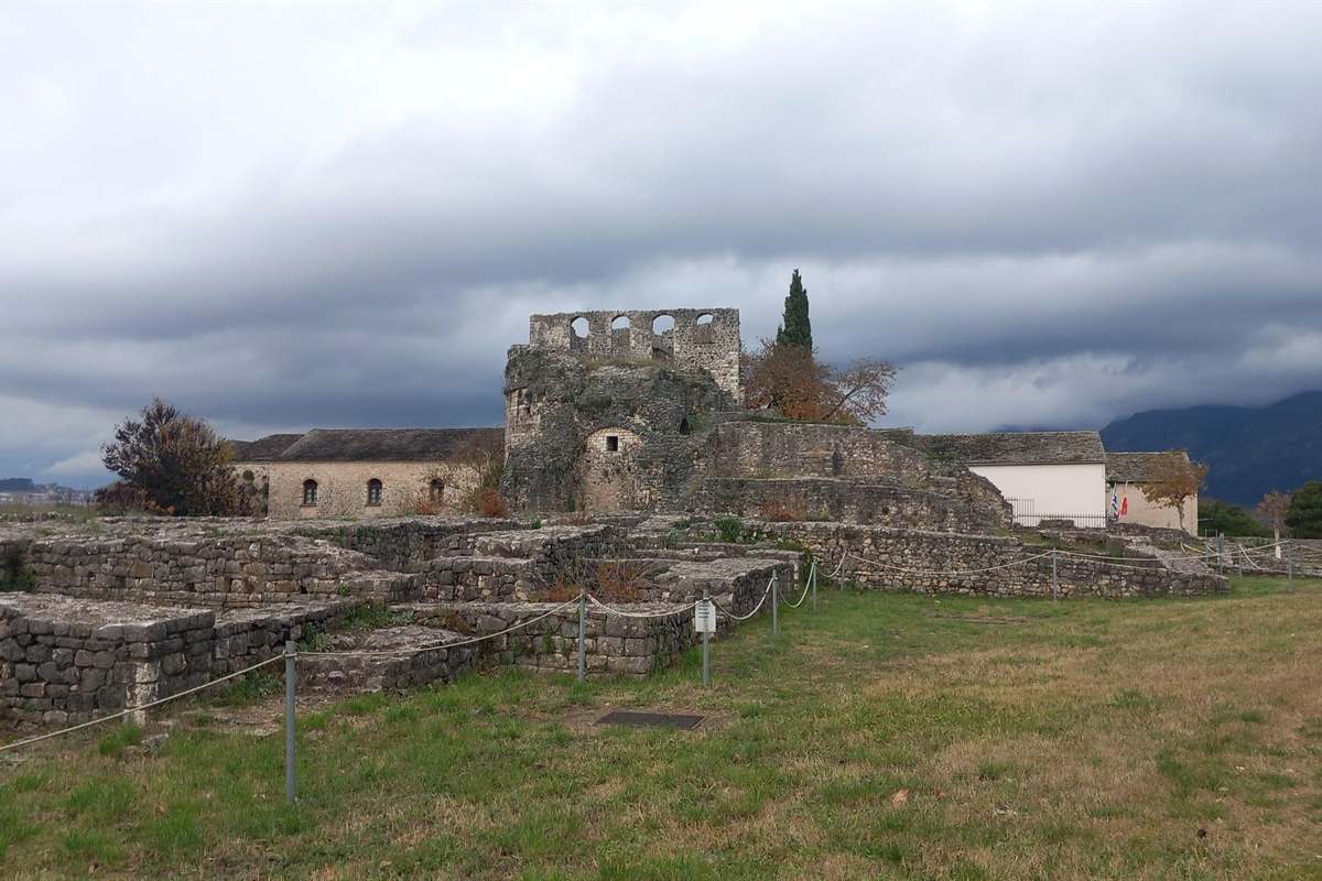 Old stone buildings and a minaret inside the castle quarter of Ioannina under a cloudy sky, a stop on an Ioannina tour