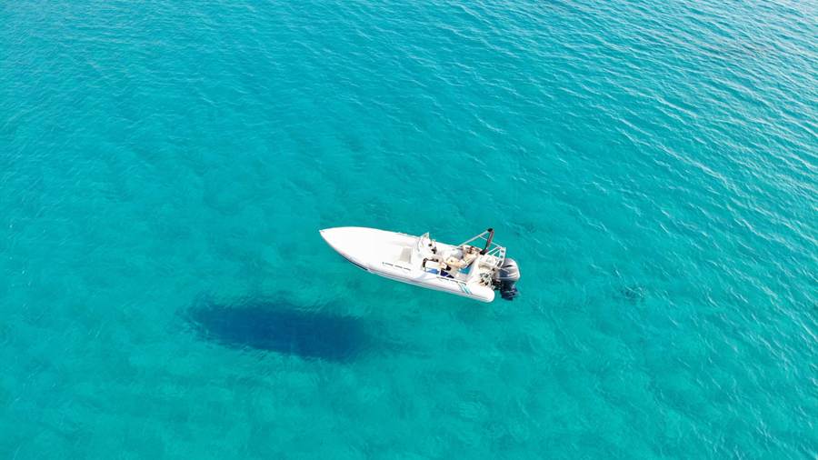 A small motor boat on turquoise water seen from above off Ios, the setting of an Ios boat trip