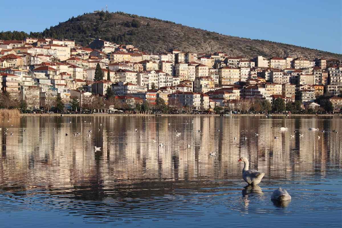 The houses of Kastoria rising above the still water of Lake Orestiada, the view at the start of a Kastoria tour