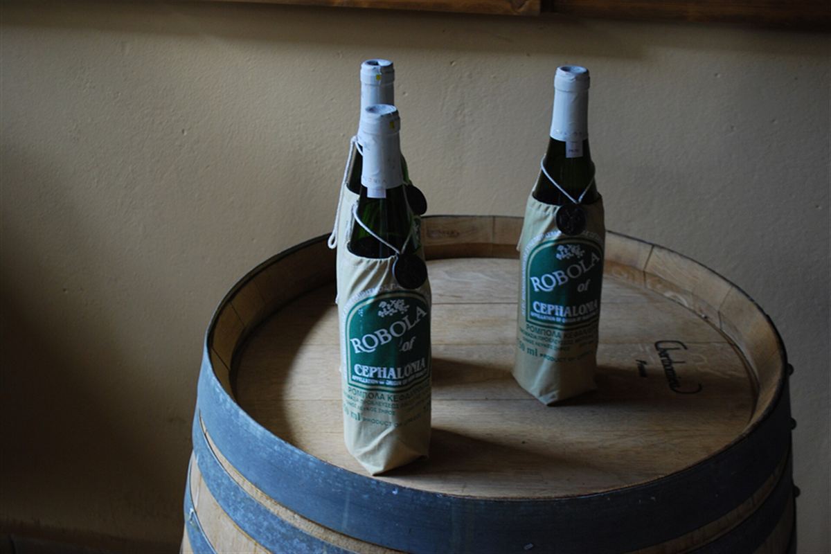 Bottles of Robola wine on an oak barrel at a Kefalonia winery, a stop on a Kefalonia wine tour