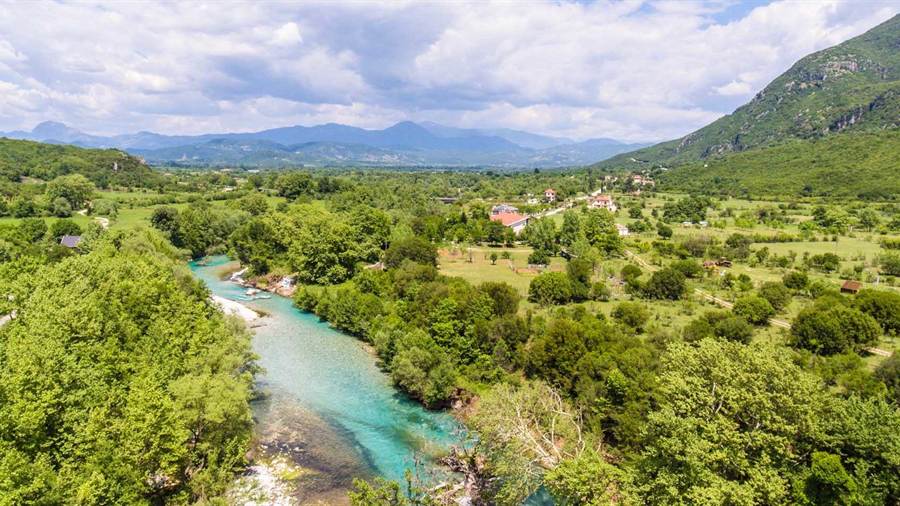 A turquoise river winding through a green valley below the mountains of Epirus, a view on a Konitsa tour