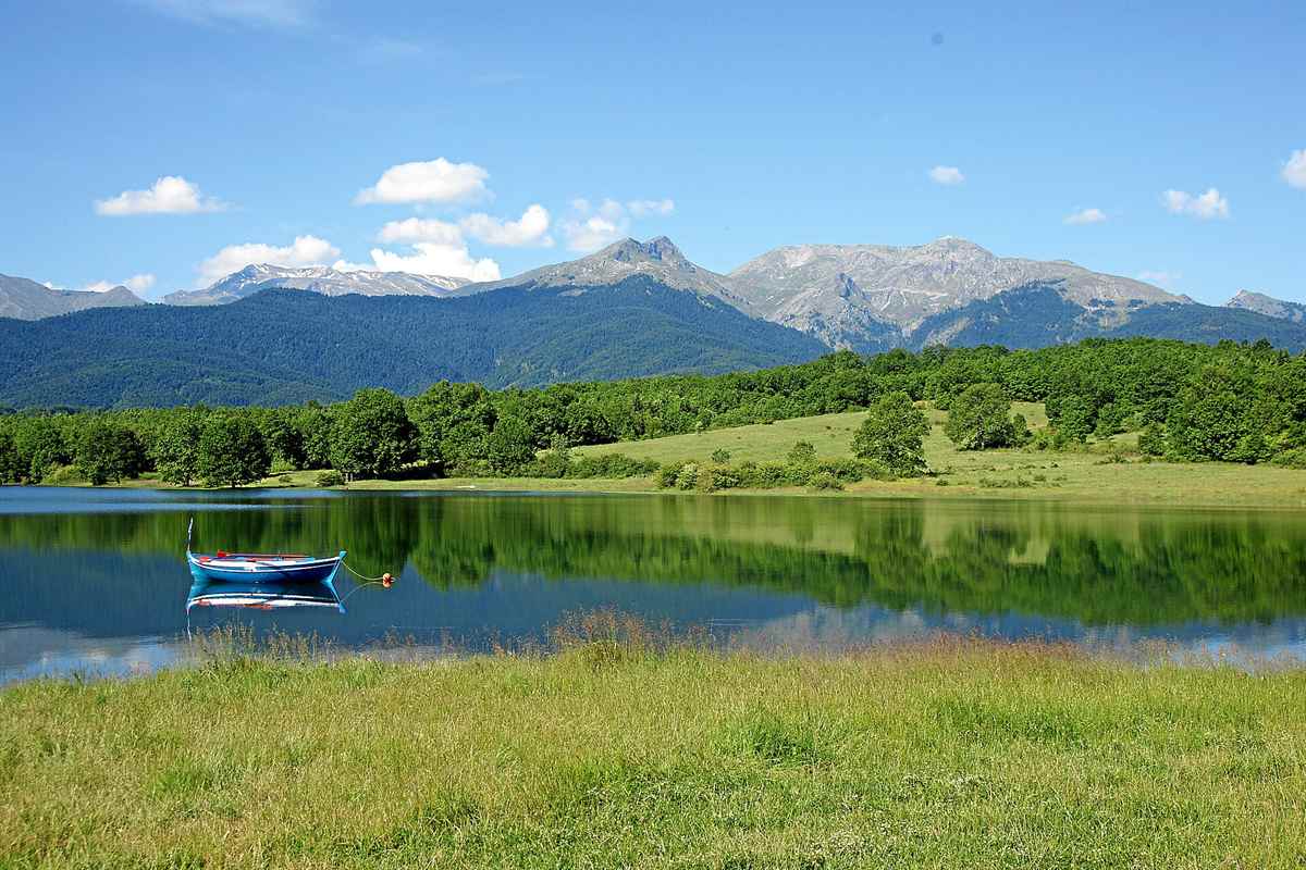 Lake Plastira with a small boat on its green shore below the Agrafa mountains