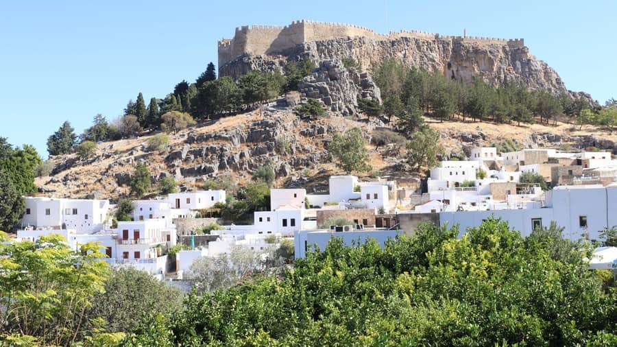 The castle walls of the Lindos acropolis above the white houses of the village on a Lindos tour