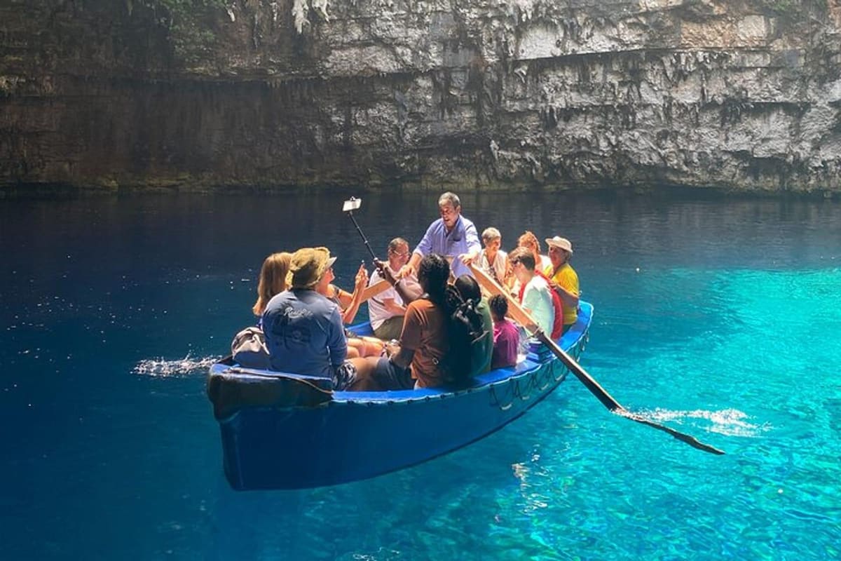 A boatman rows visitors across the turquoise lake under the rock walls on a Melissani cave tour