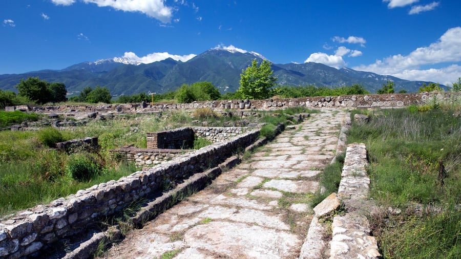 An ancient paved road runs through the ruins of Dion below the snow-capped peaks of Olympus on a Mount Olympus day trip
