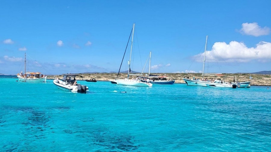 Sailboats and small boats anchored in turquoise water at a swim stop on a Naxos sailing cruise