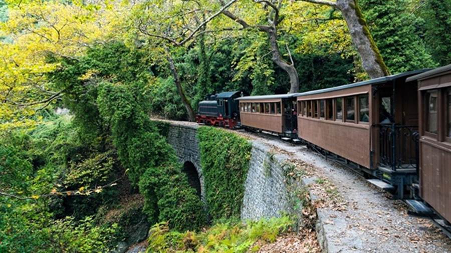 The Pelion steam train crossing a stone bridge through the trees, a ride on a Pelion tour