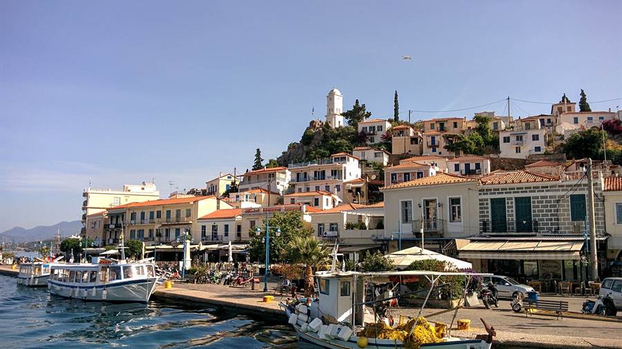 Fishing boats moored at the harbour of Poros beneath the clock tower hill