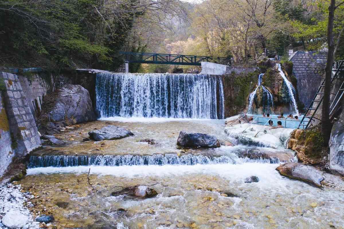 Waterfalls pouring into stepped thermal pools in a rocky gorge at the Pozar thermal baths