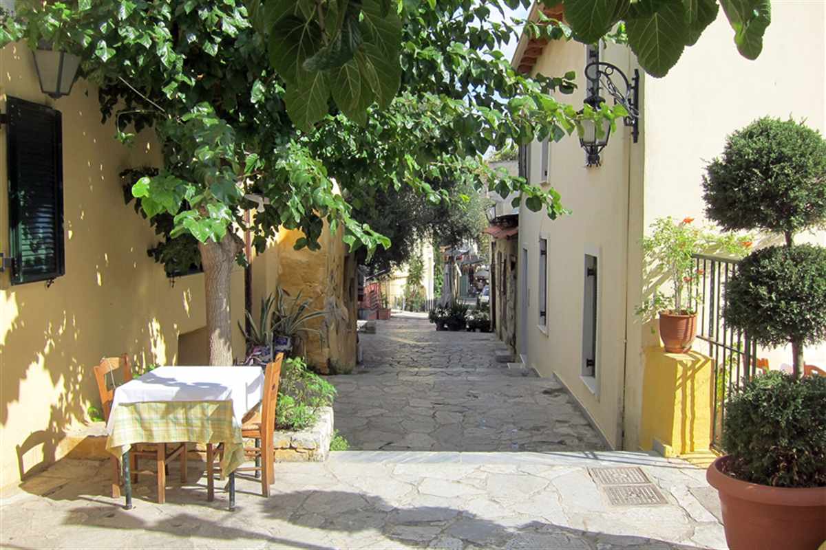 A quiet lane in Plaka with cafe tables under trees in Athens