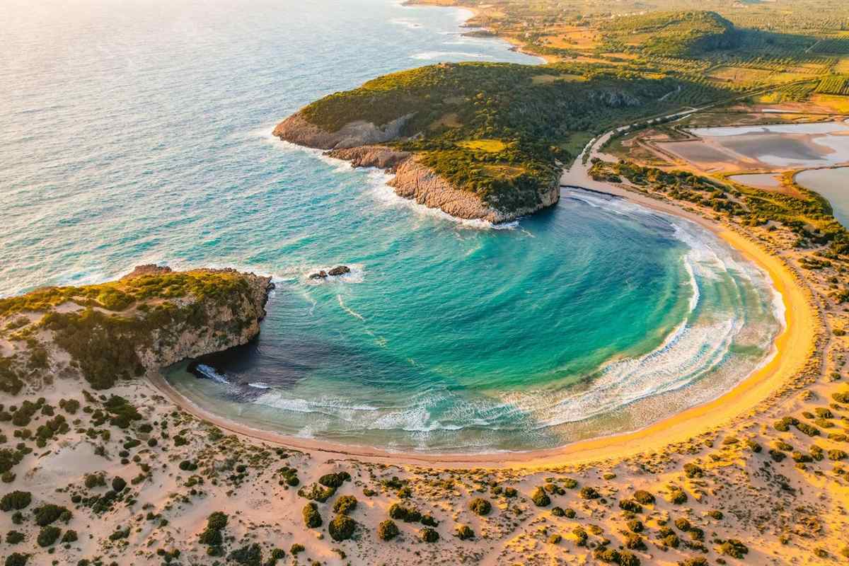 Aerial view of the curved sandy beach and turquoise bay of Voidokilia near Pylos, a stop on a Pylos tour