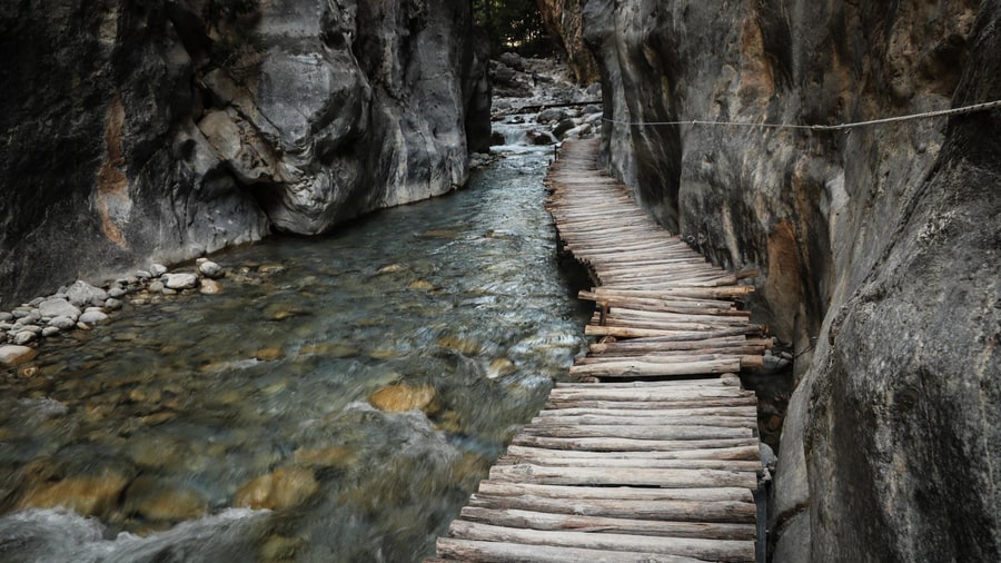 A wooden walkway runs beside the stream between the sheer rock walls of the Iron Gates on a Samaria gorge tour