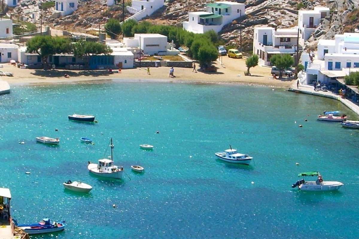 Small boats moored in a turquoise bay below white houses on Sifnos, the setting of a Sifnos boat trip