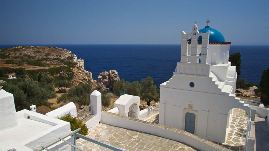 A white chapel with a blue dome on a cliff above the sea on Sifnos, seen on a Sifnos boat trip