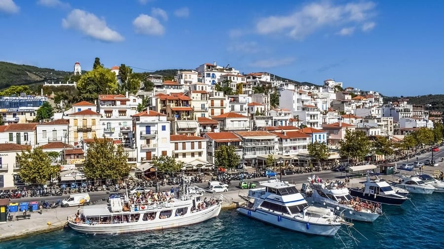Excursion boats line the harbour quay below the white houses of Skiathos town on a Skiathos boat trip