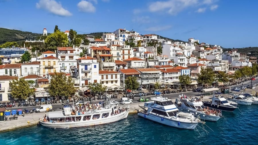 Tour boats wait at the harbour wall below the white houses of Skiathos Town on a Skiathos island tour