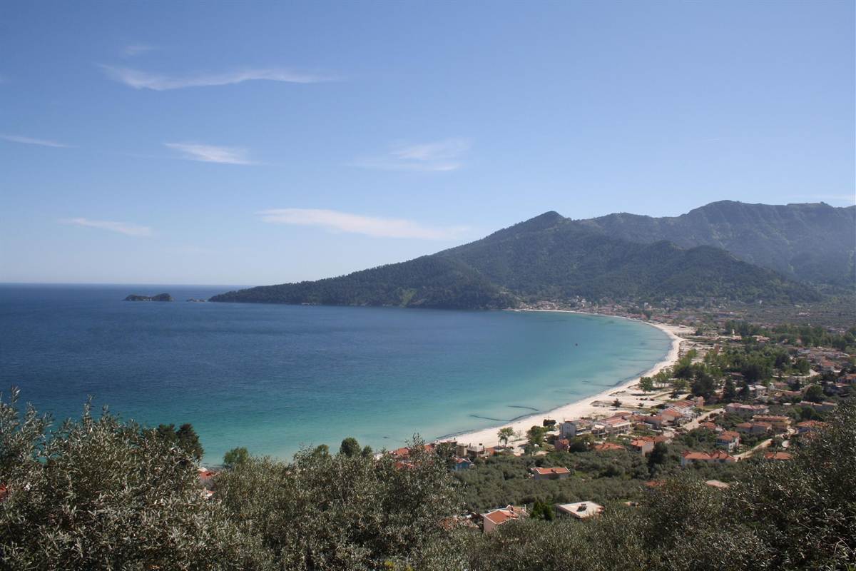 A long sandy bay on Thassos with green mountains behind, a coast seen on a Thassos boat trip